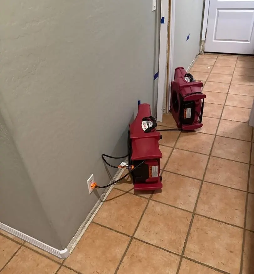 Dehumidifiers drying a tiled hallway after water damage